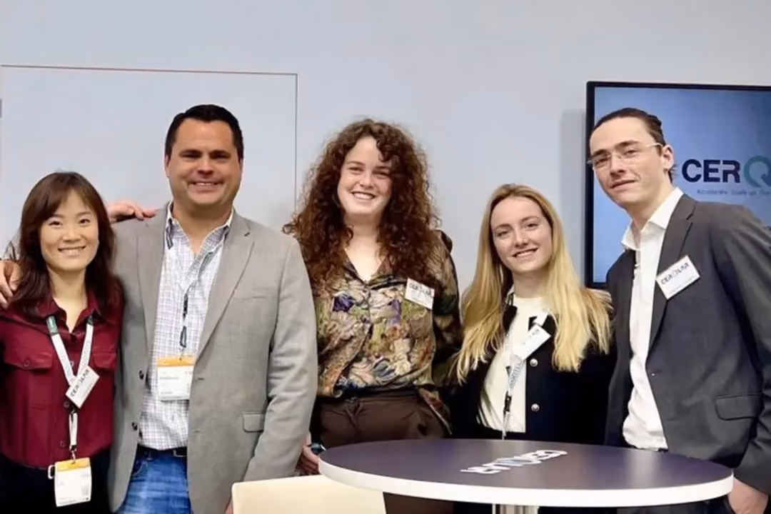 Five smiling people standing under a CERQLAR sign at a professional event or conference.