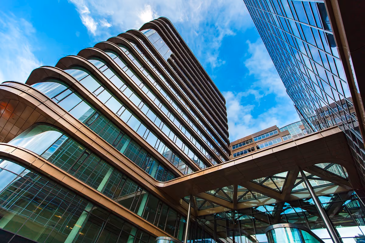 Low-angle view of modern office buildings with glass windows against a blue sky.