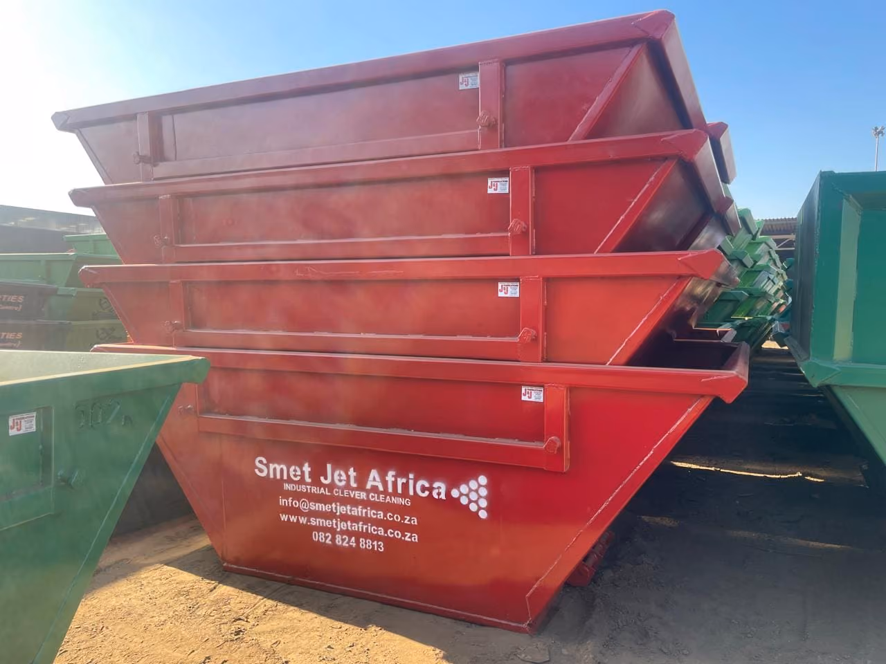 Stacked red industrial waste containers with Smet Jet Africa contact details painted on one side.