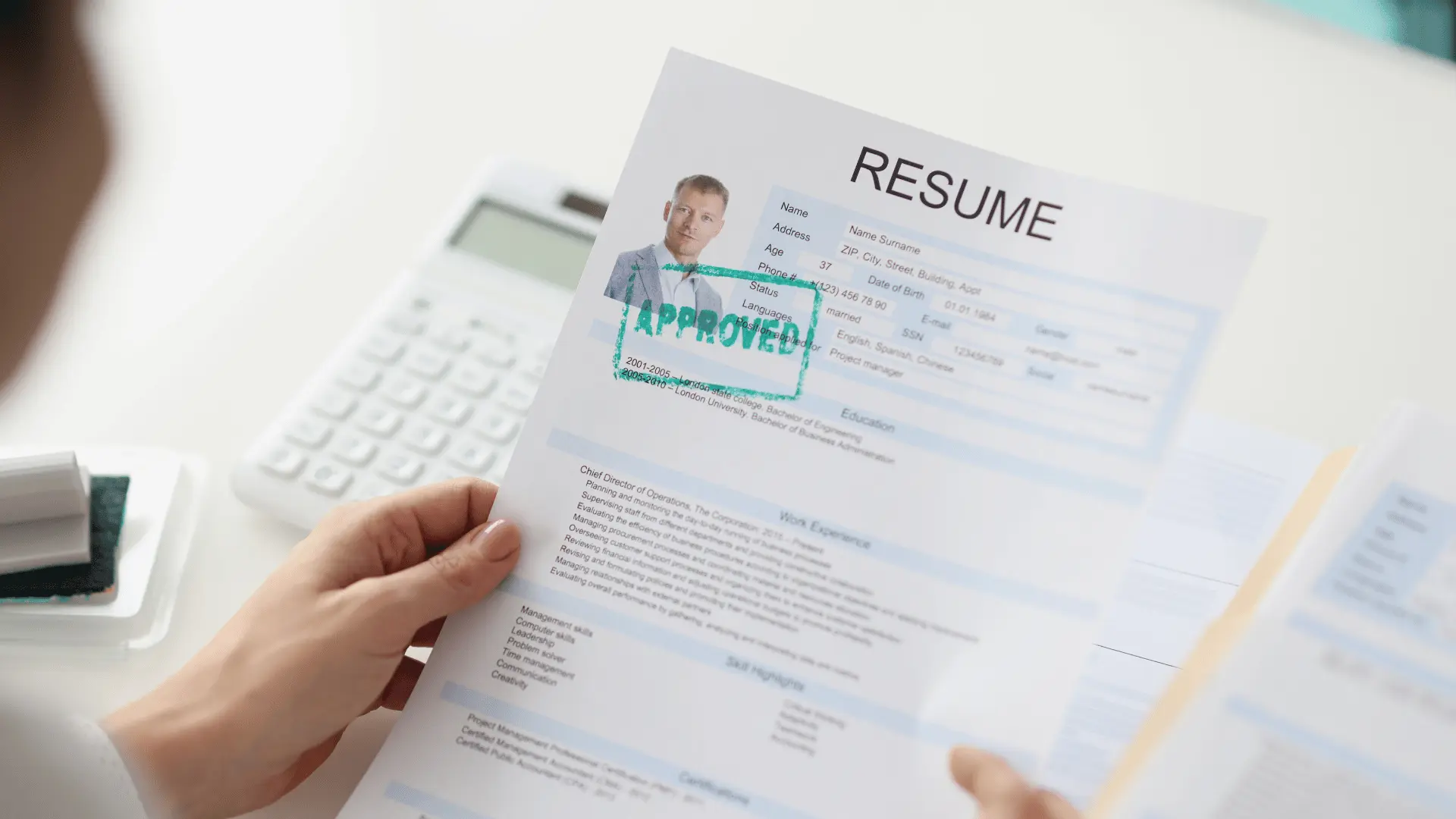Une personne tenant un CV avec une photo d'un homme et un tampon vert marqué « APPROVED », montrant que le CV est approuvé.