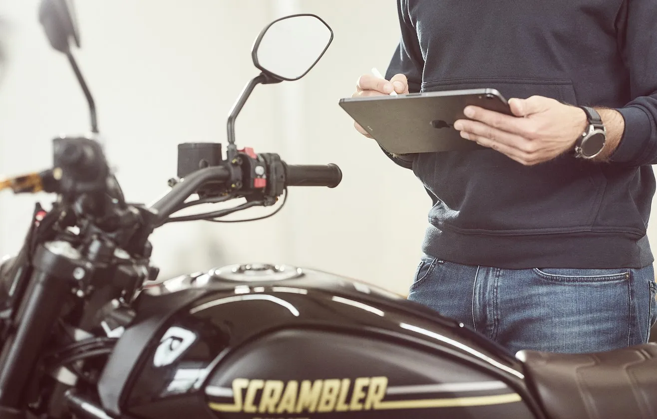 Person dokumentiert ein Motorrad mit einem Tablet