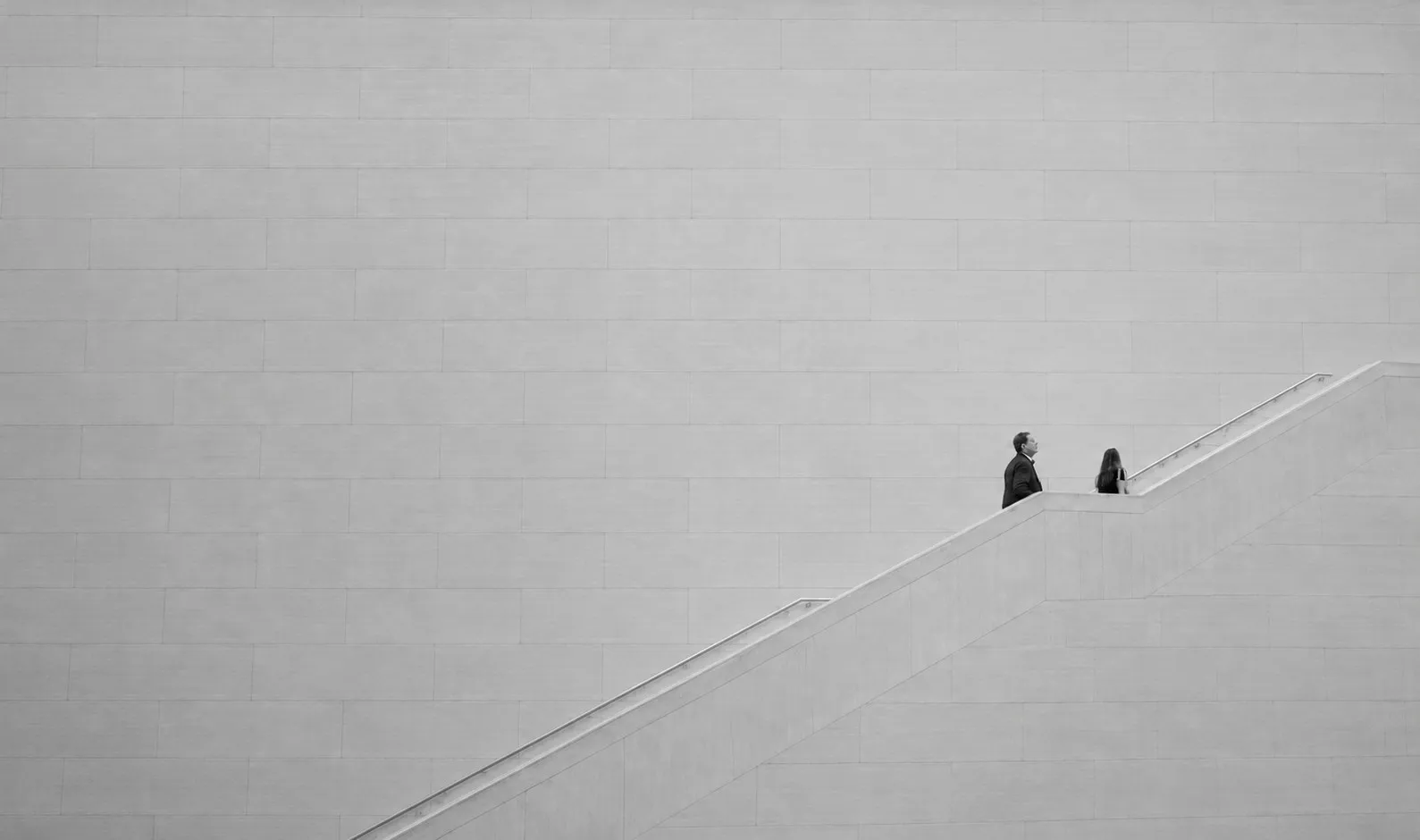 Zwei Personen auf einer Treppe in einem hellen Gebäude, Schwarzweißaufnahme