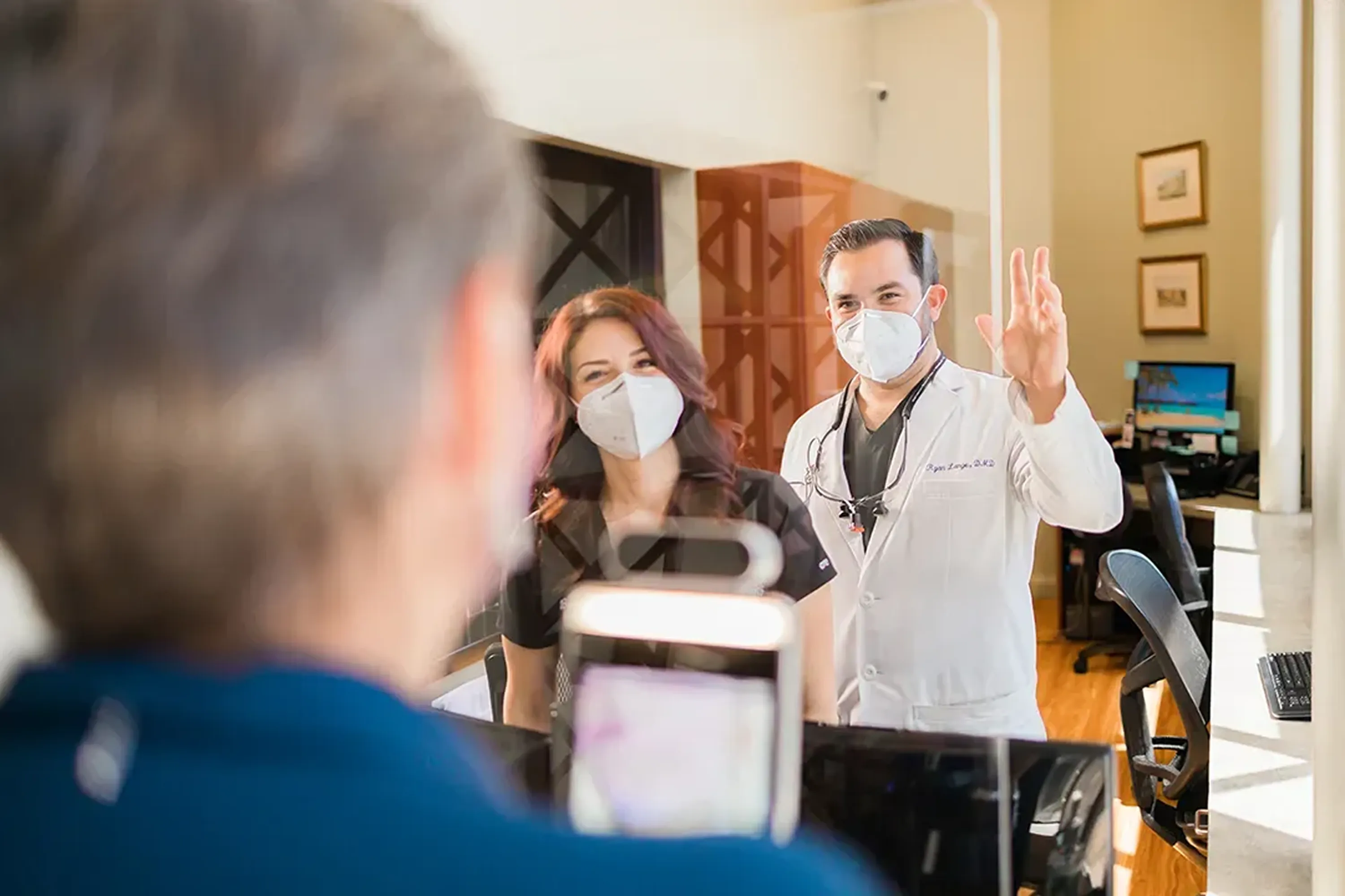Dentist and team member greeting a patient at the front desk of MacArthur Dental Arts