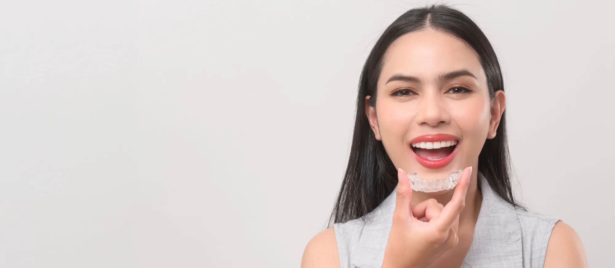 Woman holding an Invisalign clear aligner tray
