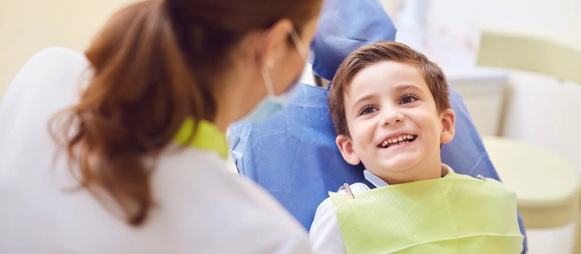 Smiling child in the dental chair talking with a dentist