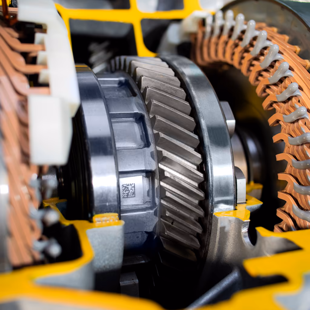 Close-up of metallic gears and copper coils inside yellow mechanical equipment.