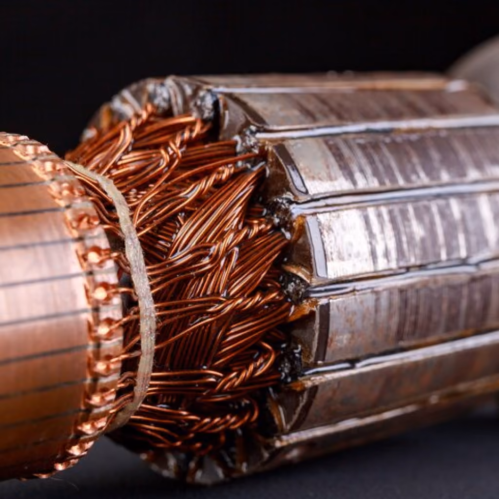 Close-up of copper wire coils and metal sections inside an electric motor rotor.