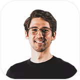 Smiling man with glasses and dark hair wearing a black shirt on a white background.