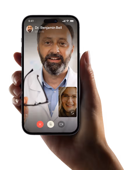 A hand holding a cell phone with a doctor on the screen.