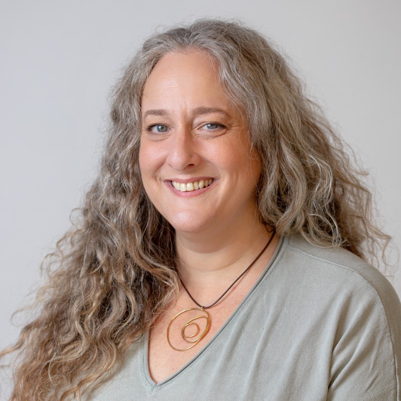 Rachel Cheyfitz, smiling, in a pale green V-neck top against a light grey background.