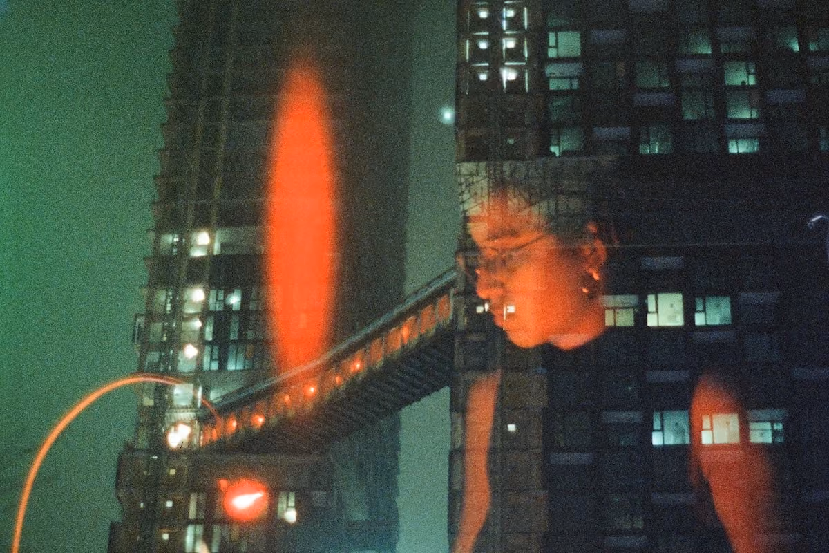 A creative blend of a woman working and towering skyscrapers at night.