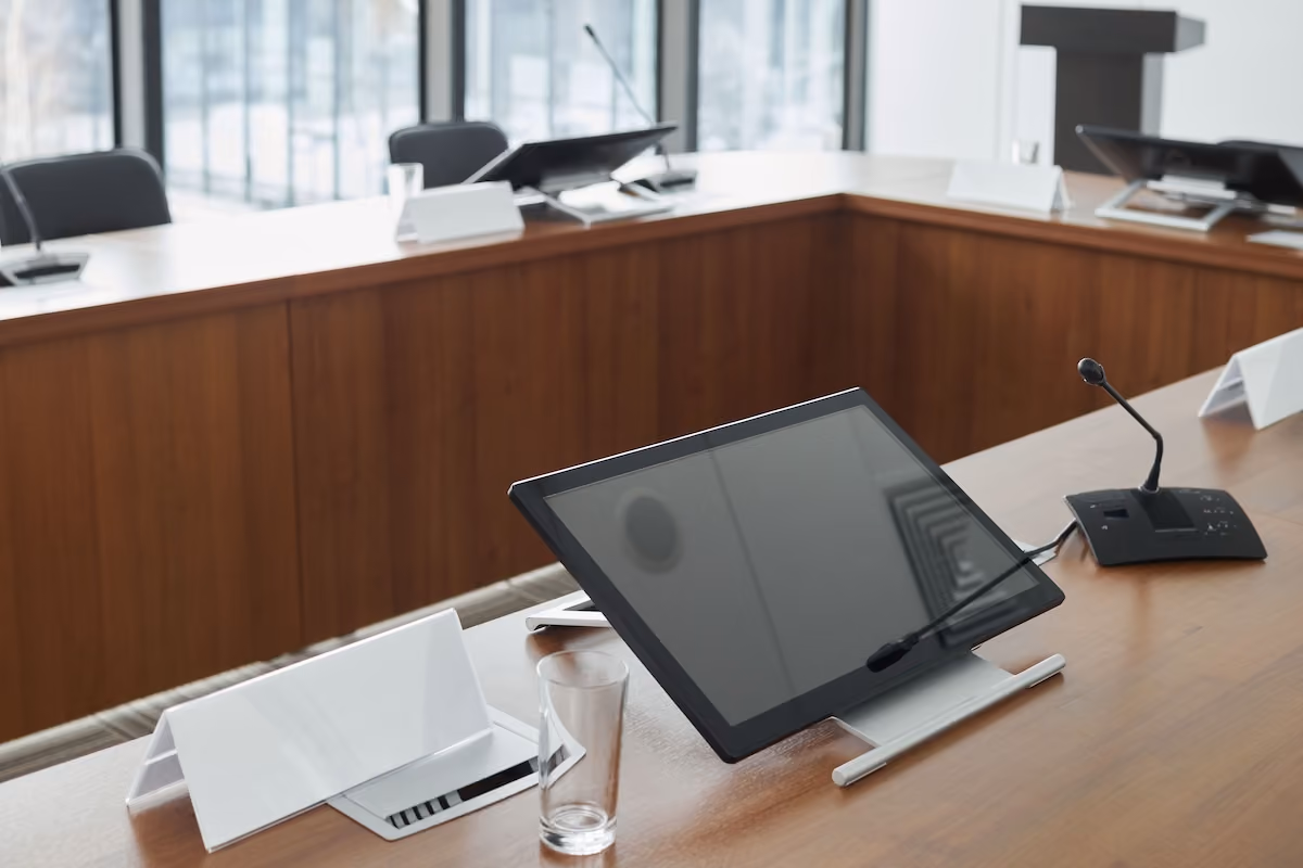 Spacious conference room equipped with digital screens and microphones, ideal for meetings.