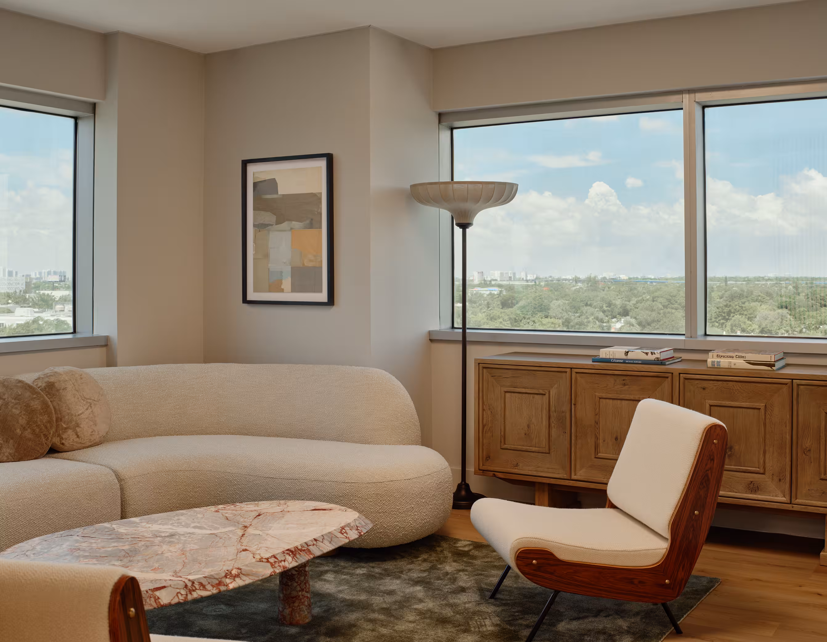 A high-rise living room with a curved sectional sofa and panoramic city views.