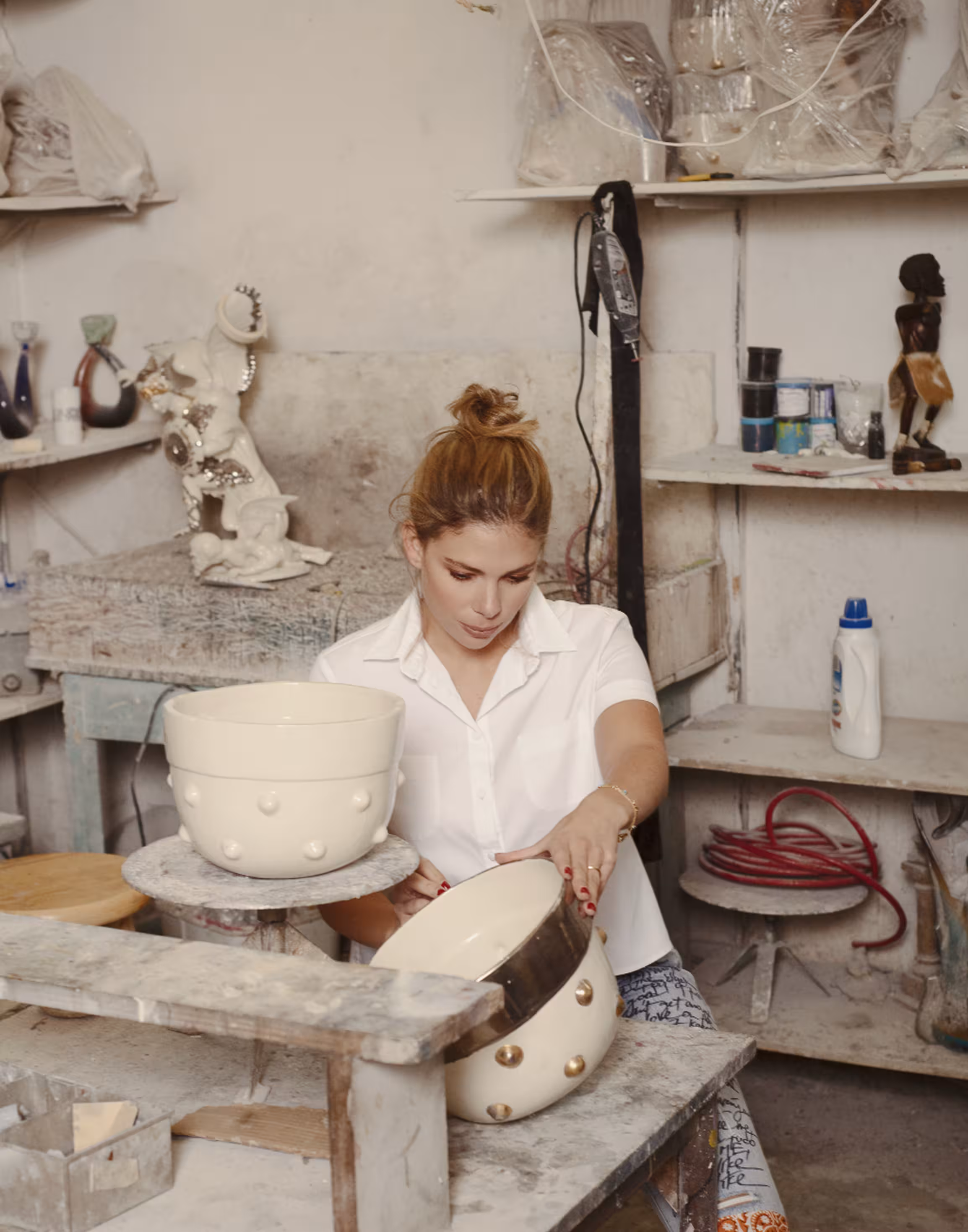 A designer hand-glazing ceramic vessels in a pottery studio.