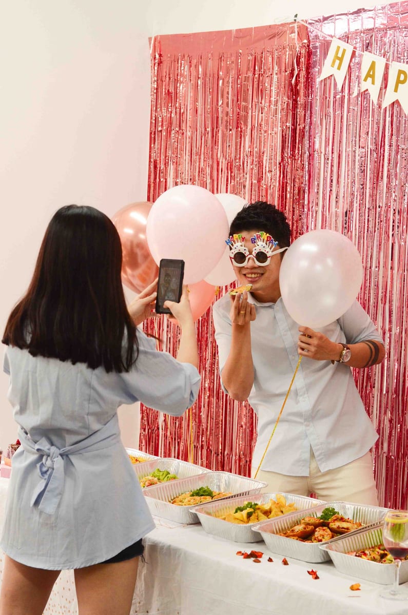 Guest in birthday glasses photographed beside iDoCatering buffet trays at a 2022 birthday party