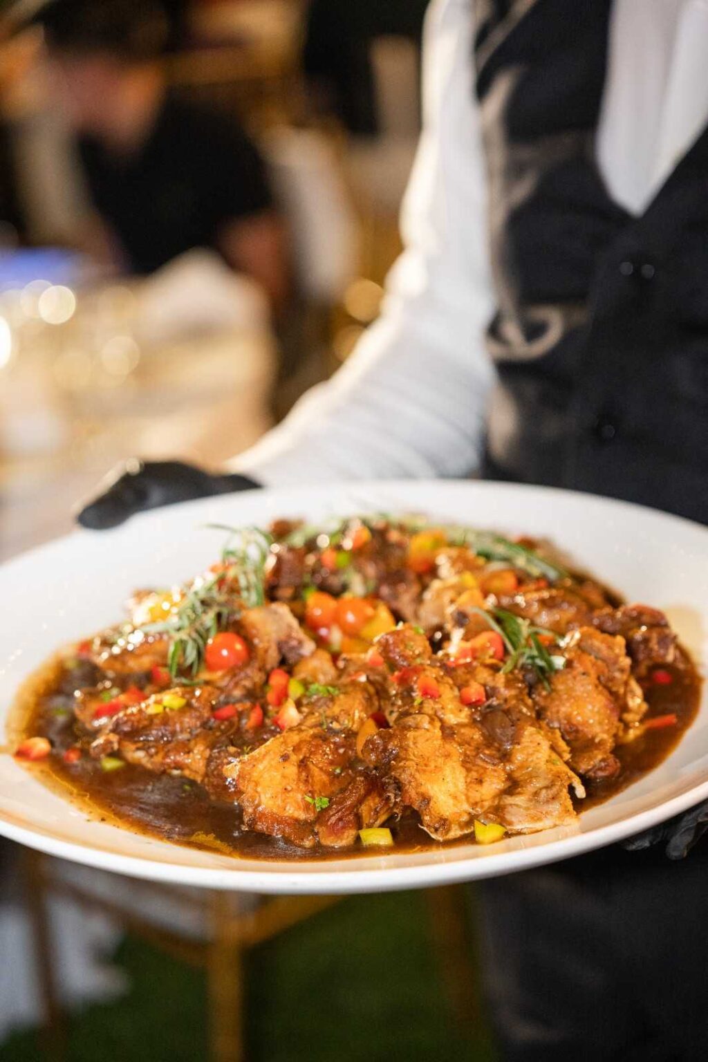 iDoCatering server presenting braised chicken with cherry tomatoes and rosemary at the AEON biker event 2025