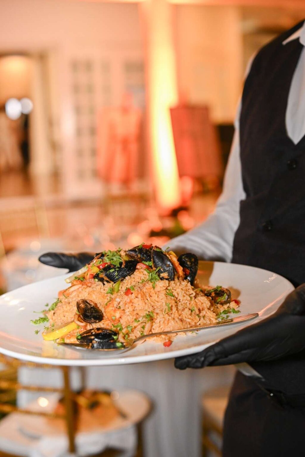 Server presenting seafood rice with mussels and parsley at the AEON biker event, catered by iDoCatering