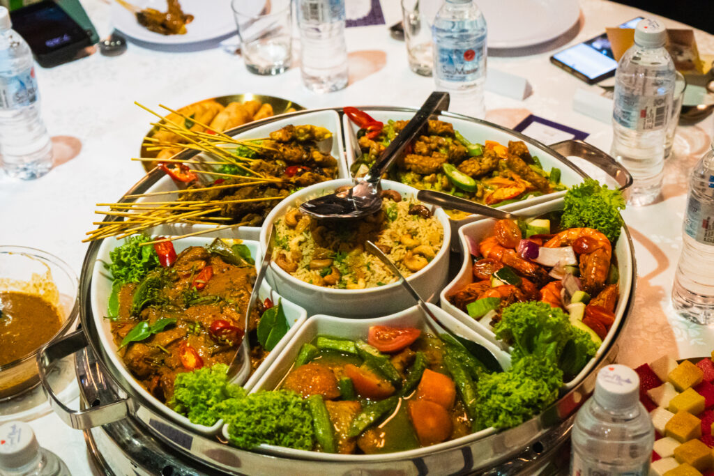 Round-table platter of satay, curries, prawns, vegetables and nut rice at a corporate dinner by iDoCatering