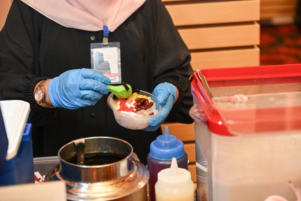 Staff preparing a bowl of ais kacang at the live dessert station, Hari Raya corporate event at Mercu UEM