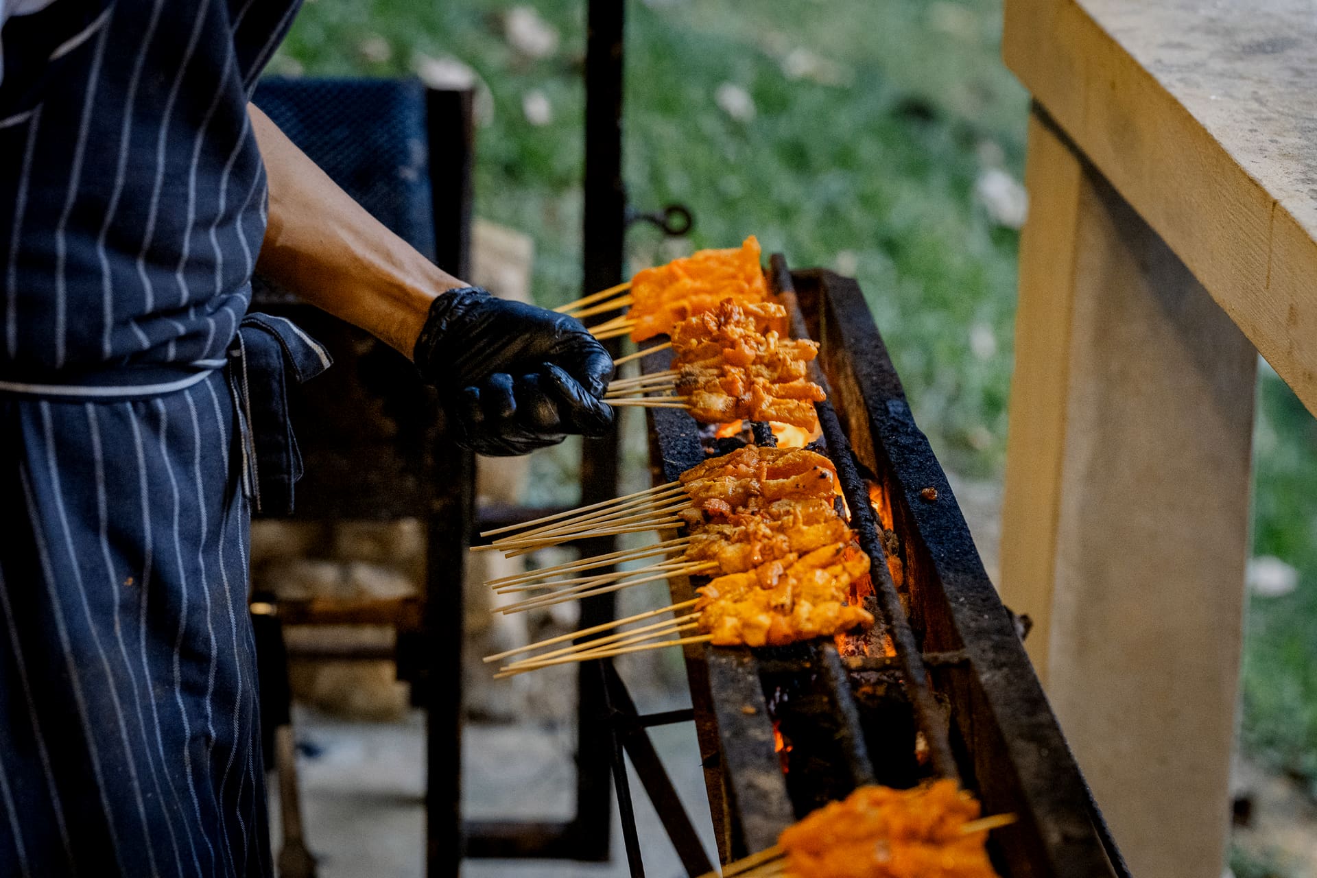 iDoCatering chef laying chicken satay skewers over glowing charcoal at an outdoor live station in Kuala Lumpur