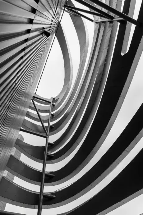 Black and white photo of a curved multi-level parking structure from inside looking up.