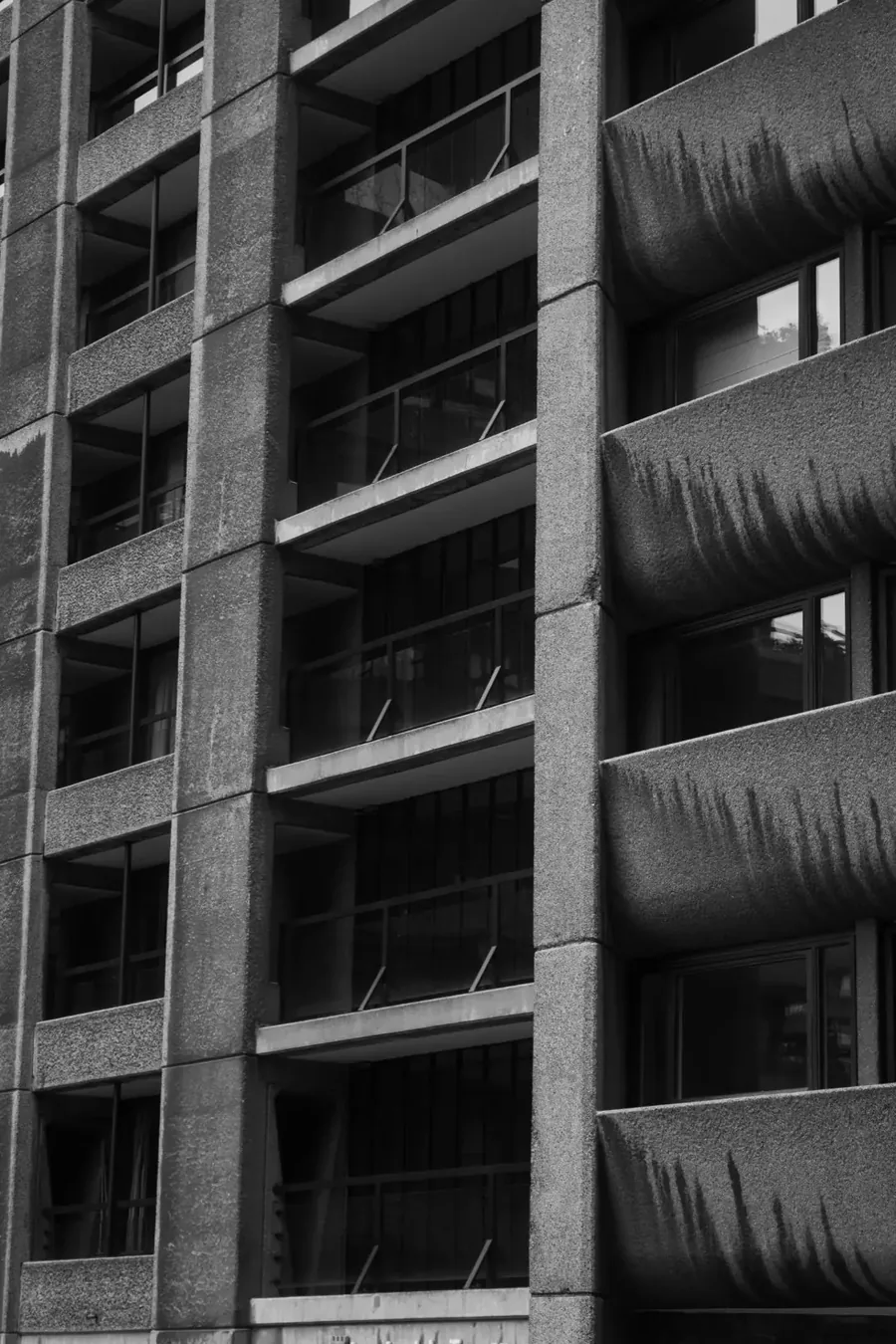 Black and white close-up of a sculpted concrete building facade with balconies and windows.