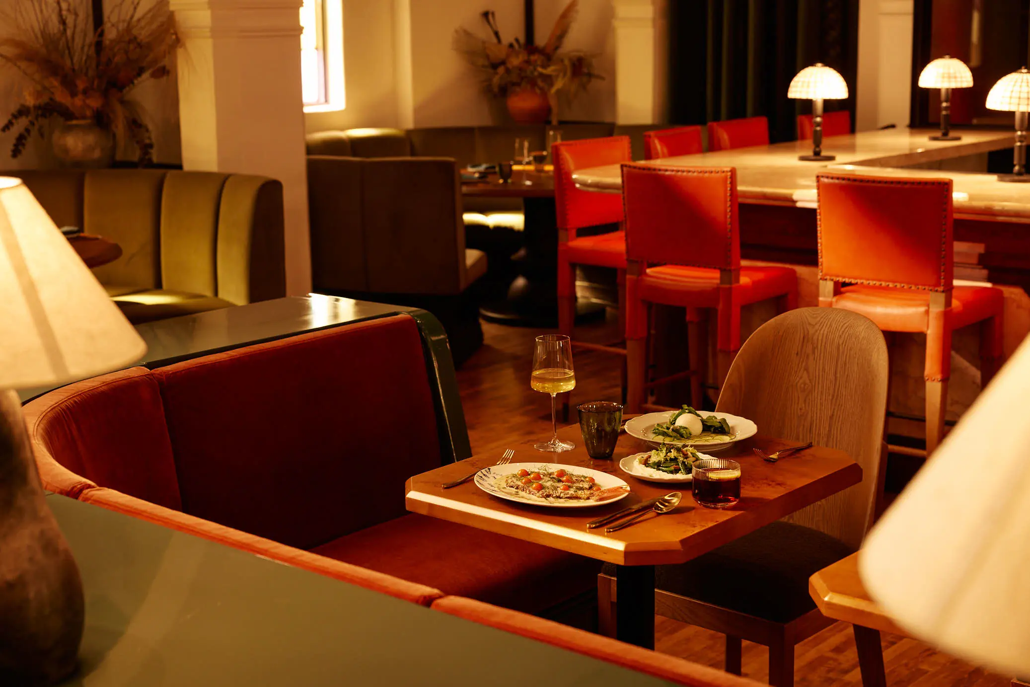 A dining room at Sous Sous set with red chairs and table lamps