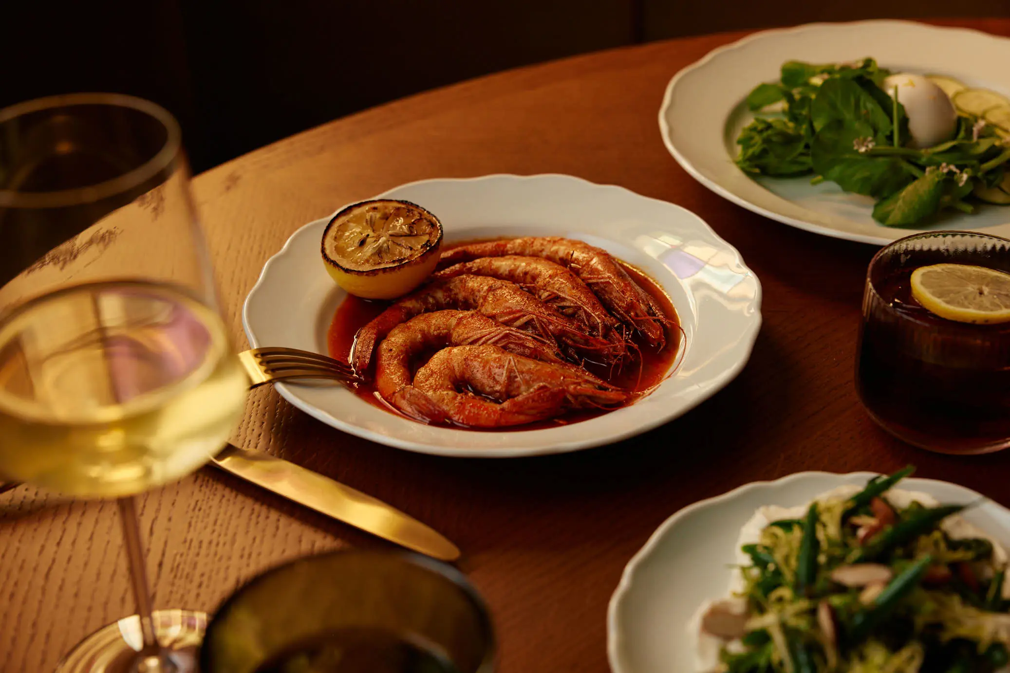 A table of shared dishes including prawns and green salads