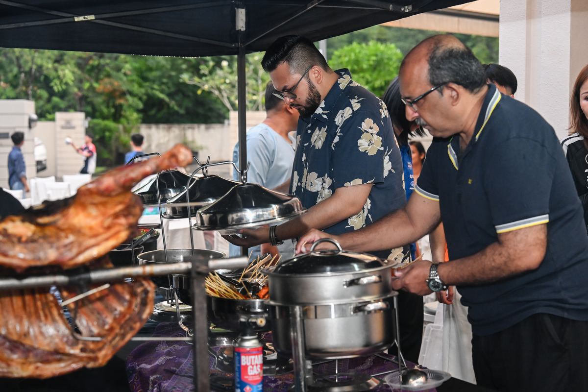 Guests enjoying iDoCatering buffet line at a small event in KL — satay and chafing dishes