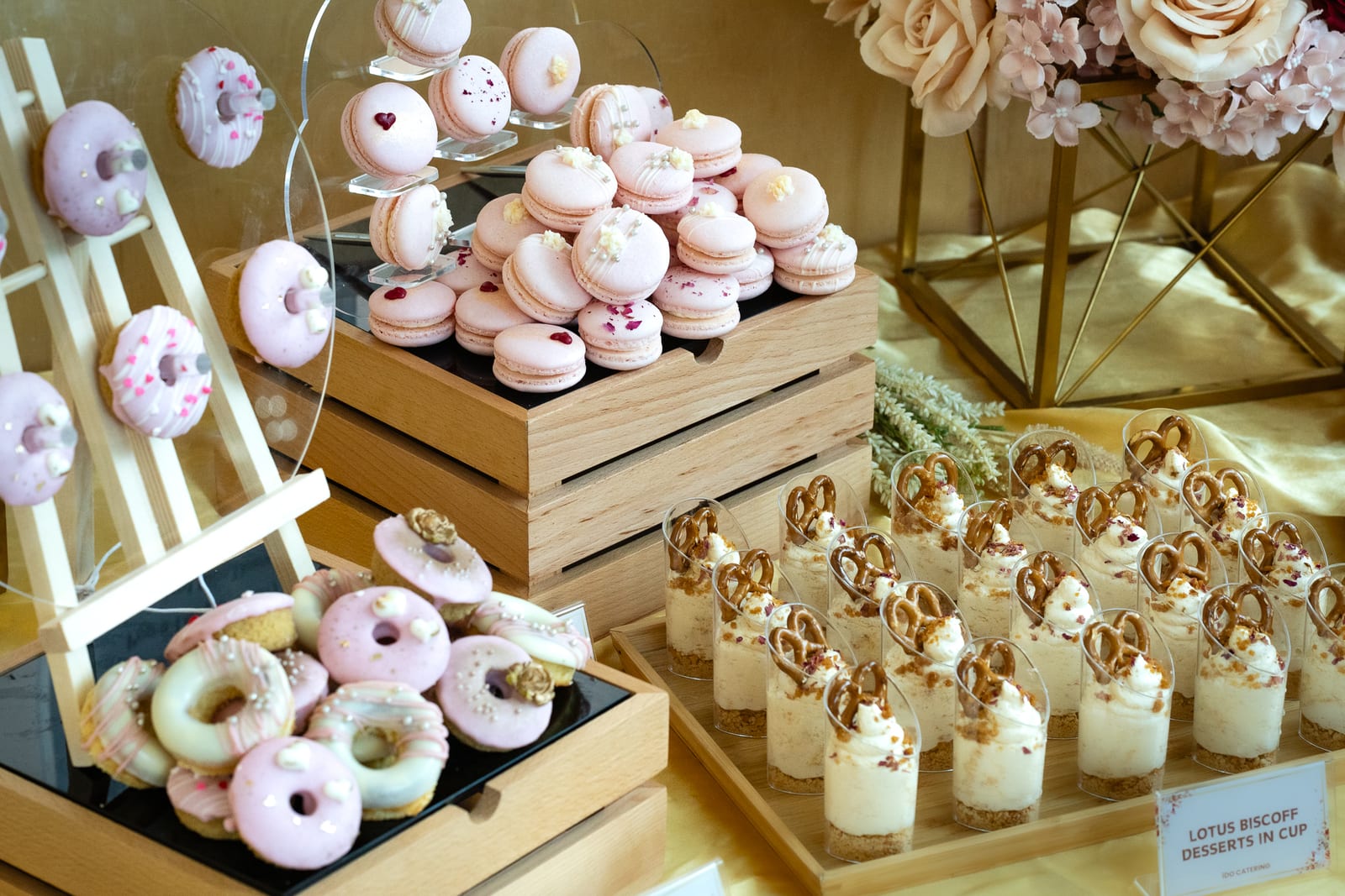 Wedding dessert table with pink macarons, iced donuts and Lotus Biscoff cups — iDoCatering KL