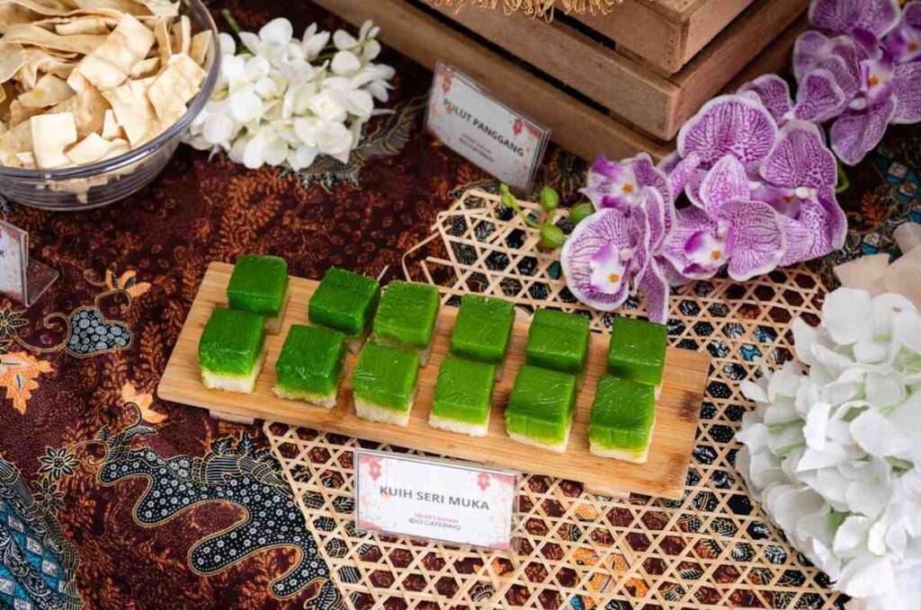 Kuih seri muka pandan squares on a wooden board with keropok, from the iDoCatering Ramadan and Raya menu