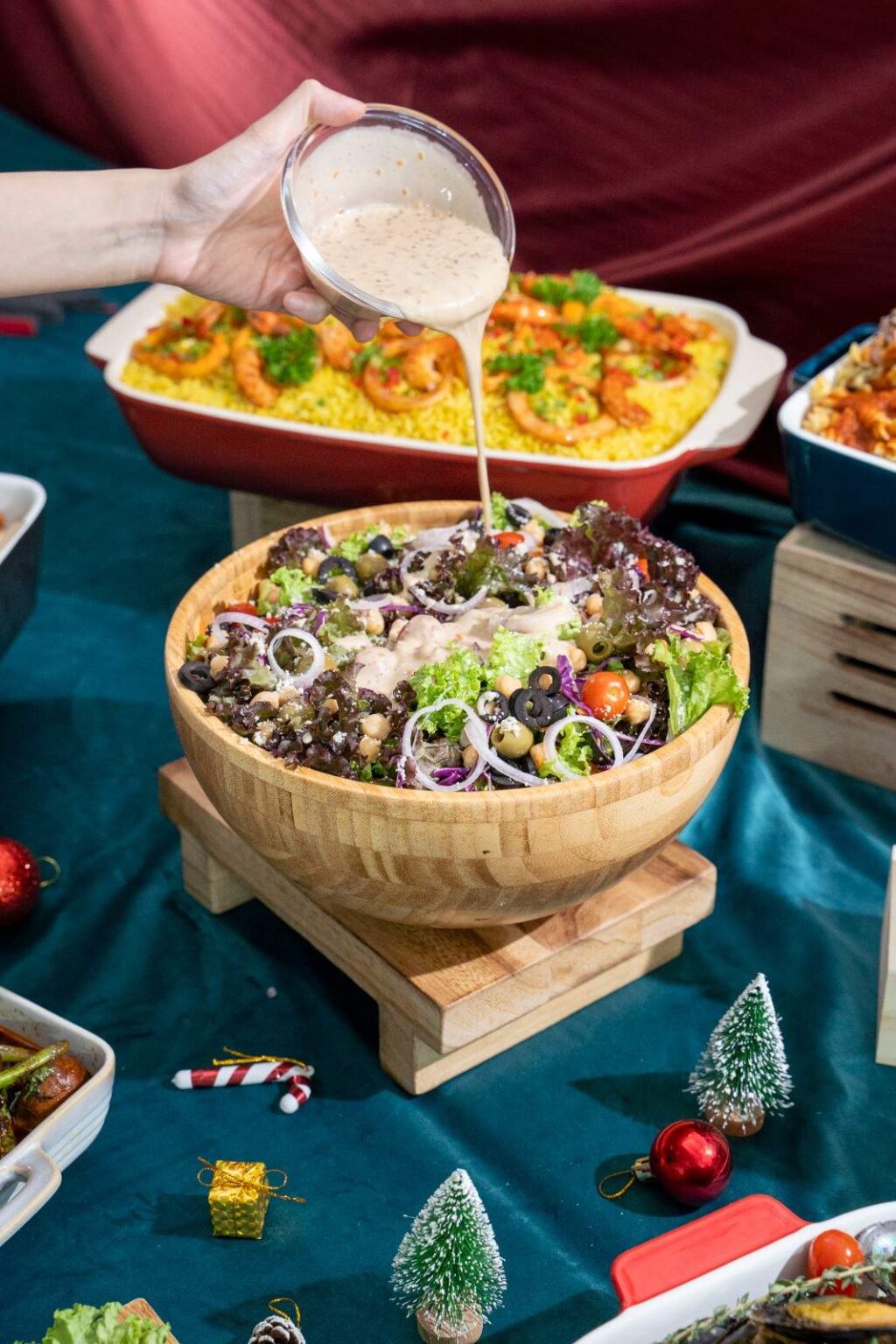 Creamy dressing poured over a garden salad of mixed leaves, chickpeas and olives at an iDoCatering Christmas buffet