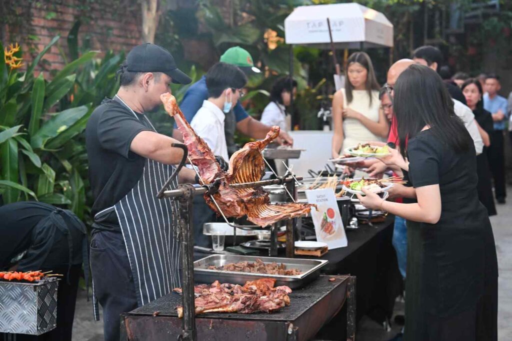 iDoCatering chef carving spit-roasted lamb at a live station as guests plate their food