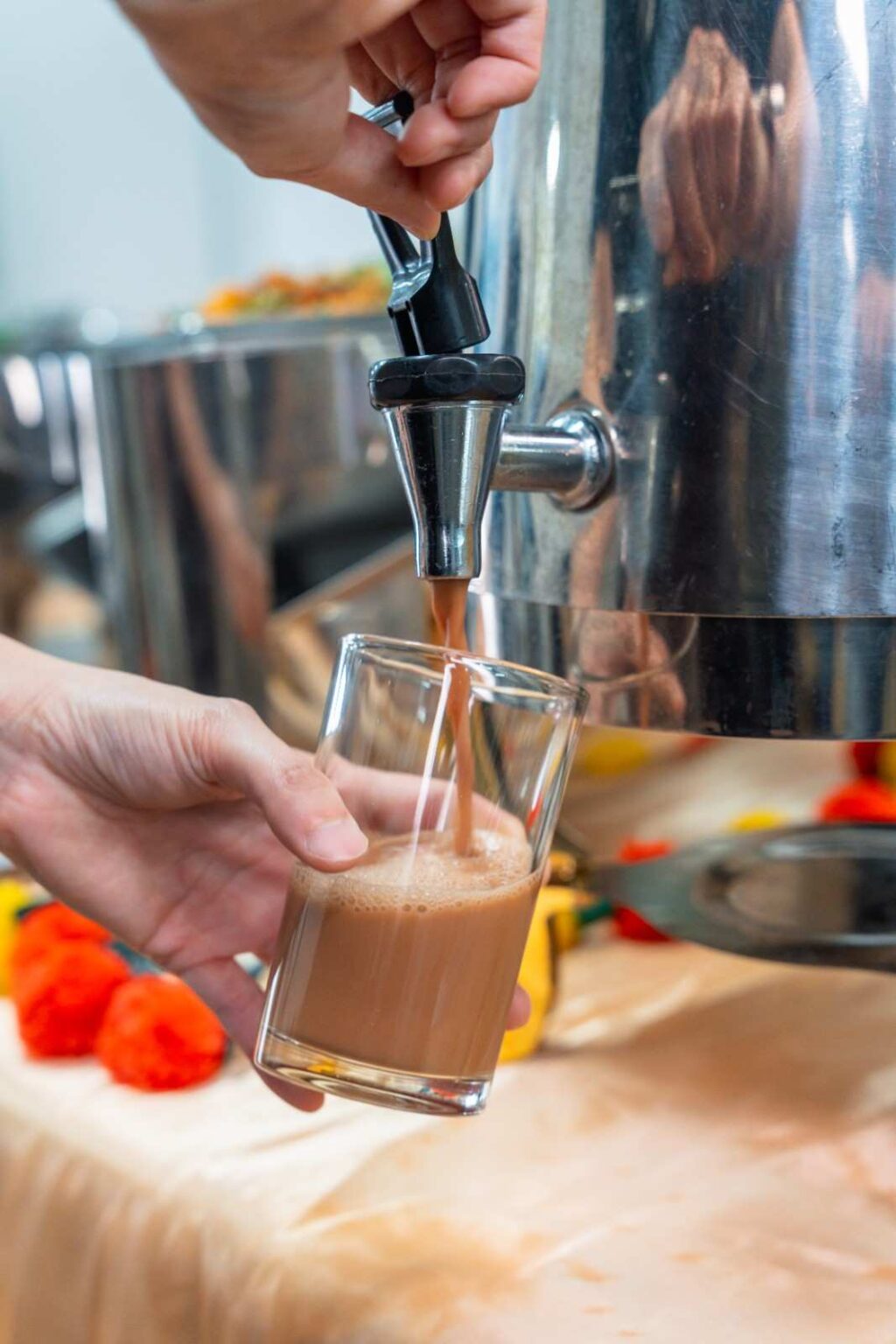 Hot teh tarik poured from a stainless urn at an office Deepavali catering by iDoCatering, 2025