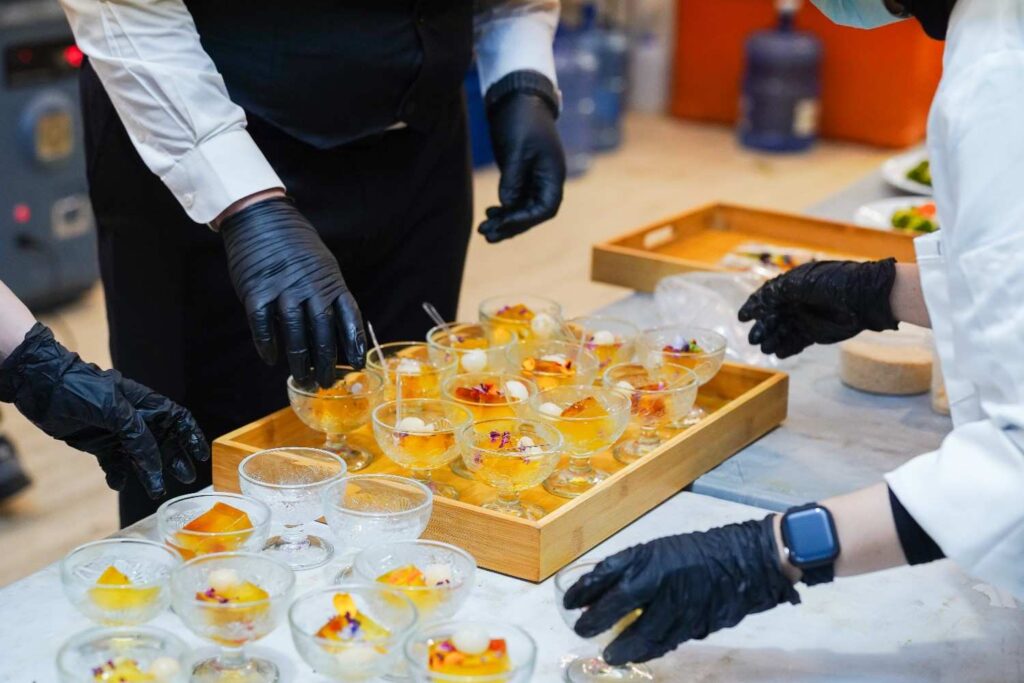 iDoCatering staff plating jelly and lychee dessert cups in glass coupes at the AEON biker event 2025