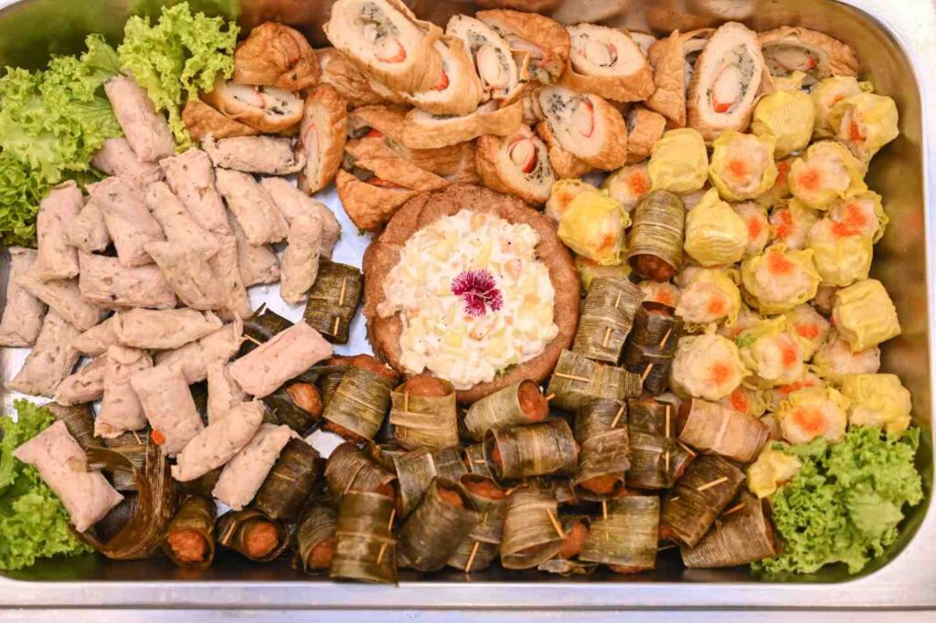 Tray of siew mai, pandan-wrapped sausages, stuffed rolls and potato salad - iDoCatering finger food catering