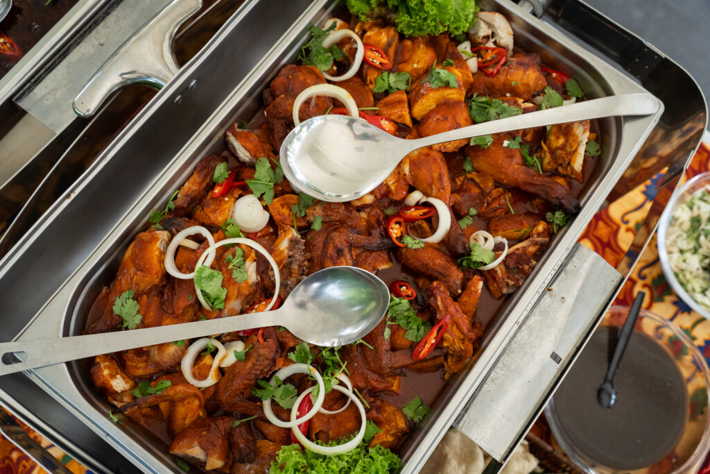 Chafing dish of ayam masak merah with onion rings, chilli and coriander at an iDoCatering Malay wedding buffet
