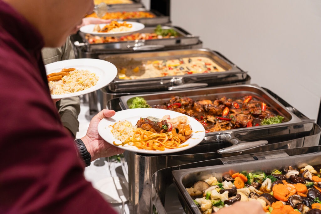 Guest serving rice and noodles from an iDoCatering buffet line of chafing dishes at a celebration