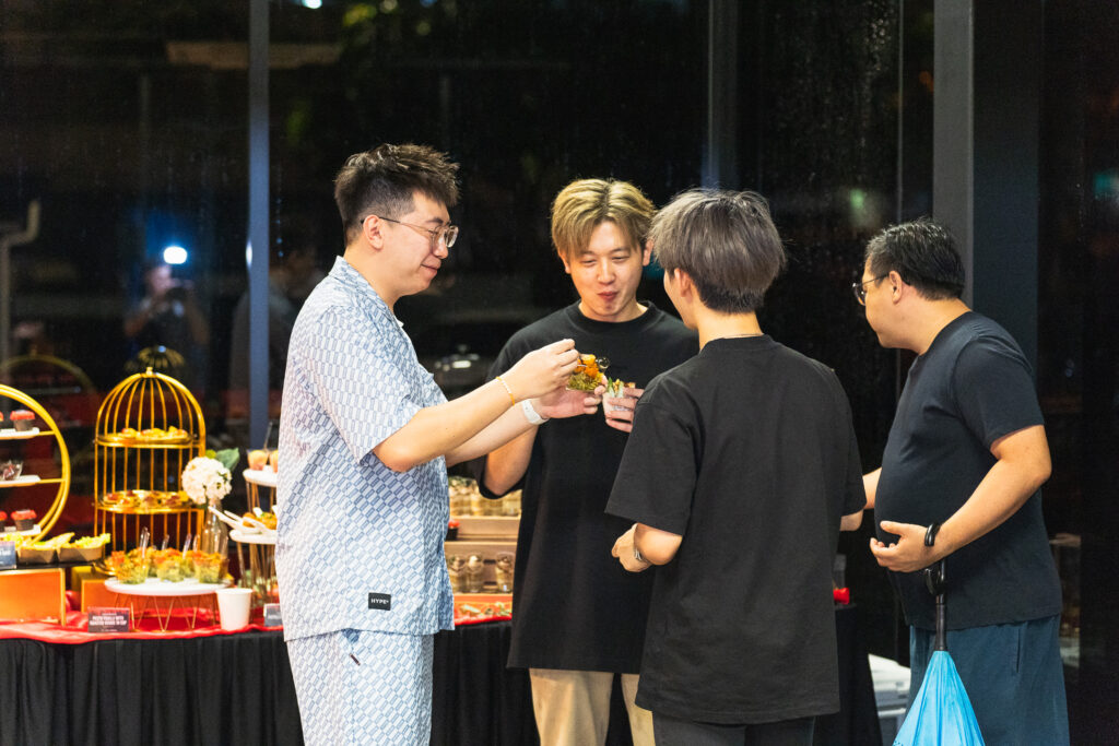 Guests tasting iDoCatering canape cups beside a gold-stand dessert table at an evening corporate event