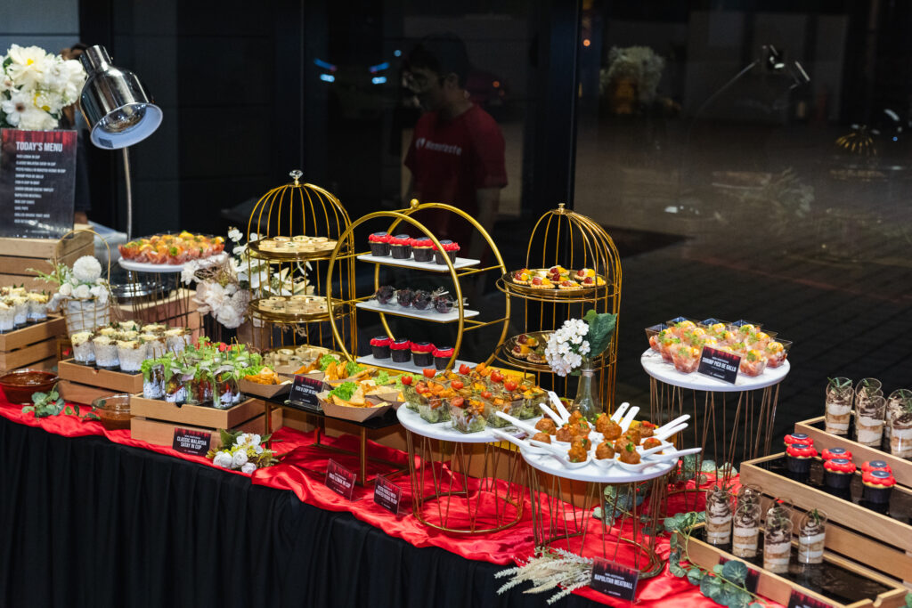 iDoCatering canape spread with a printed menu board, gold birdcage stands and labelled cups at a corporate event