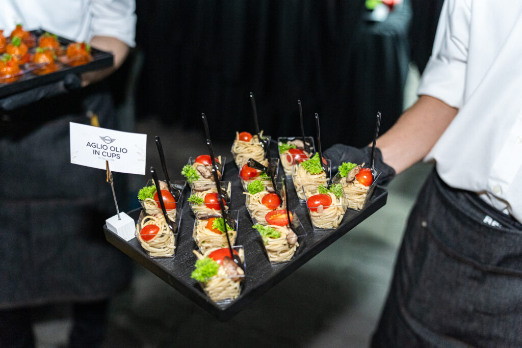 Aglio olio in cups with cherry tomato and parsley, passed on a black tray at the MINI Cooper launch