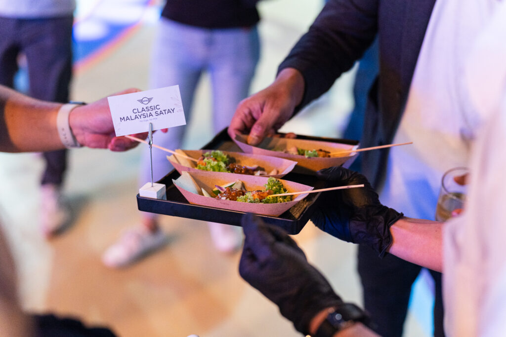 Server passing Classic Malaysia Satay boats with a labelled card at the Mini Cooper launch, by iDoCatering