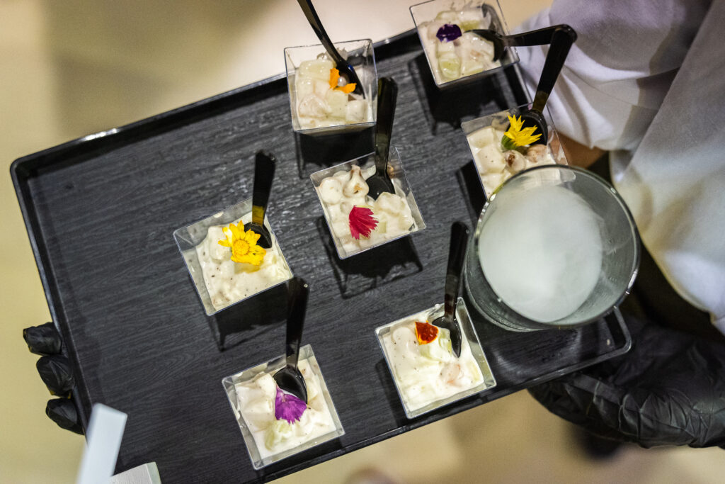 Tray of honey dew shrimp shooters topped with edible flowers for walk-around canapé service at a car launch