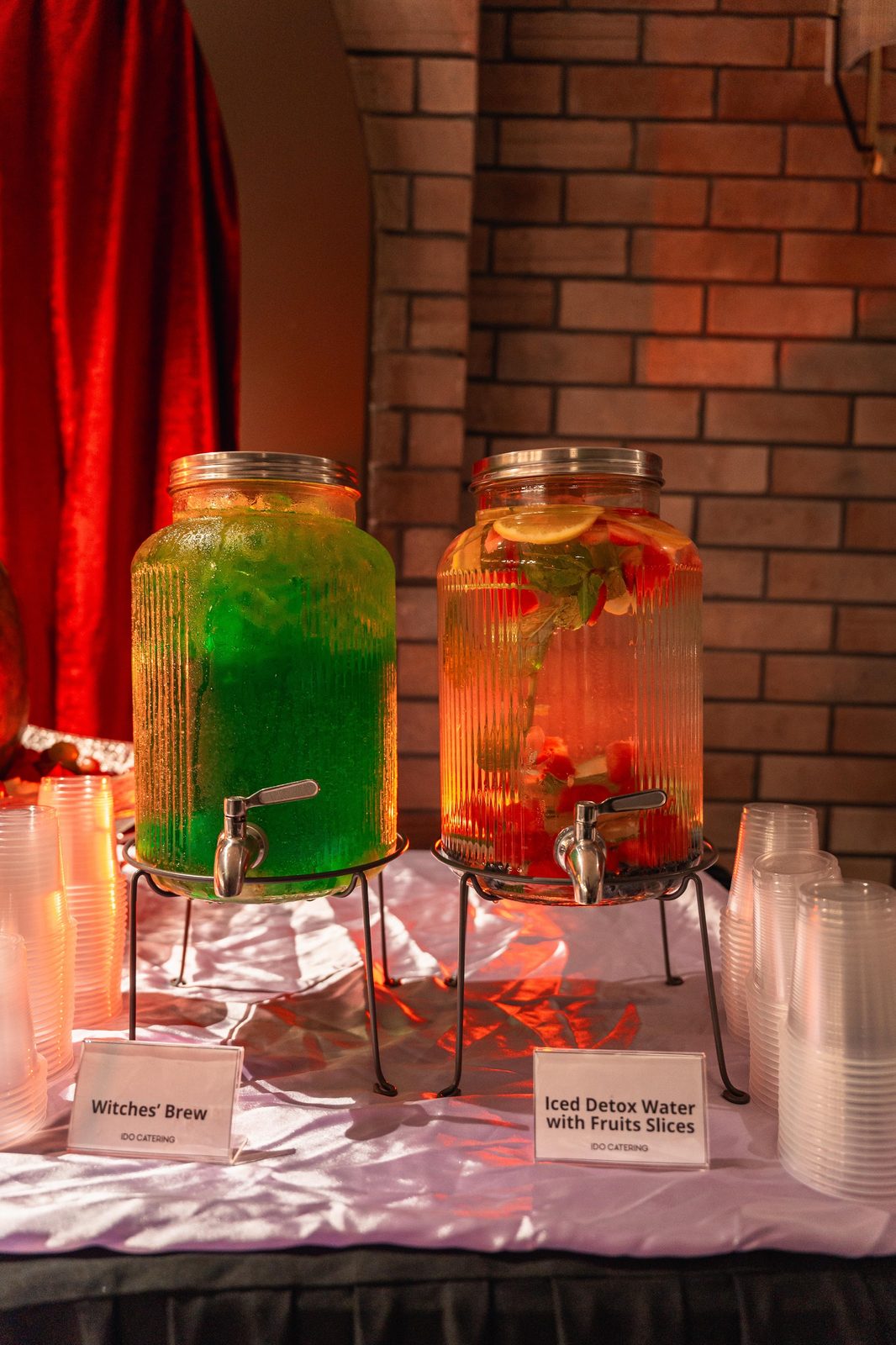 Witches' Brew and iced detox water dispensers with labels at an iDoCatering Halloween party drinks table