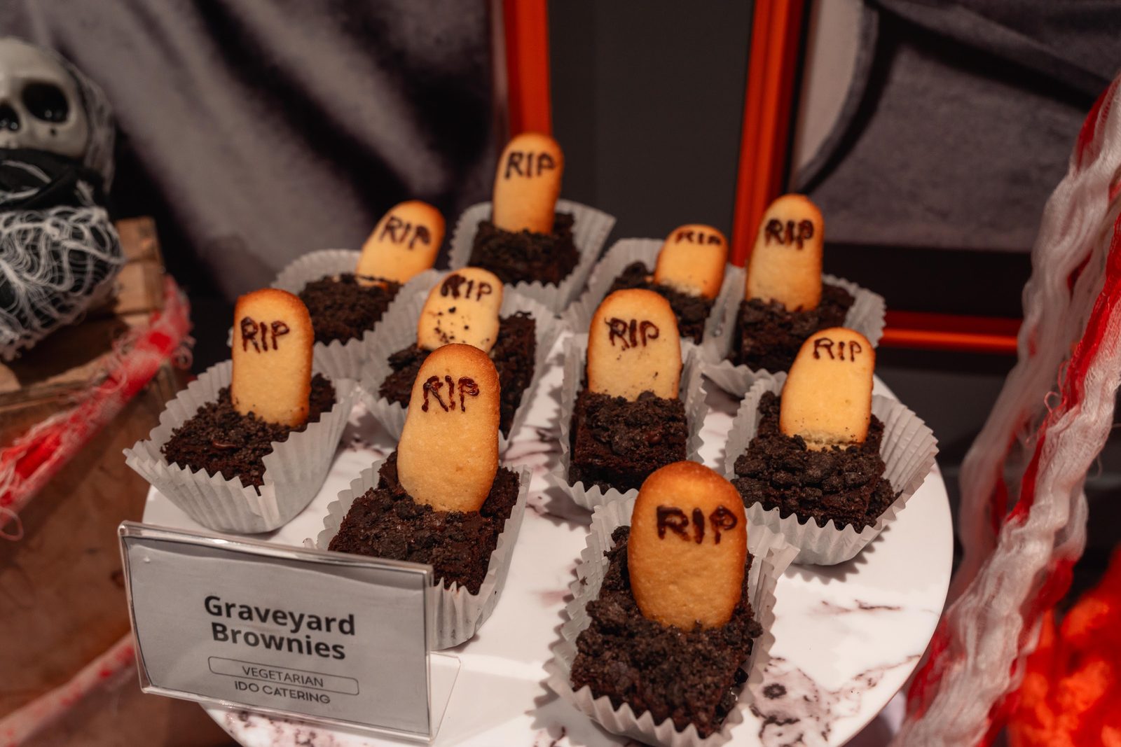 Graveyard Brownies with RIP sponge tombstones in cookie-crumb soil at an iDoCatering Halloween dessert table