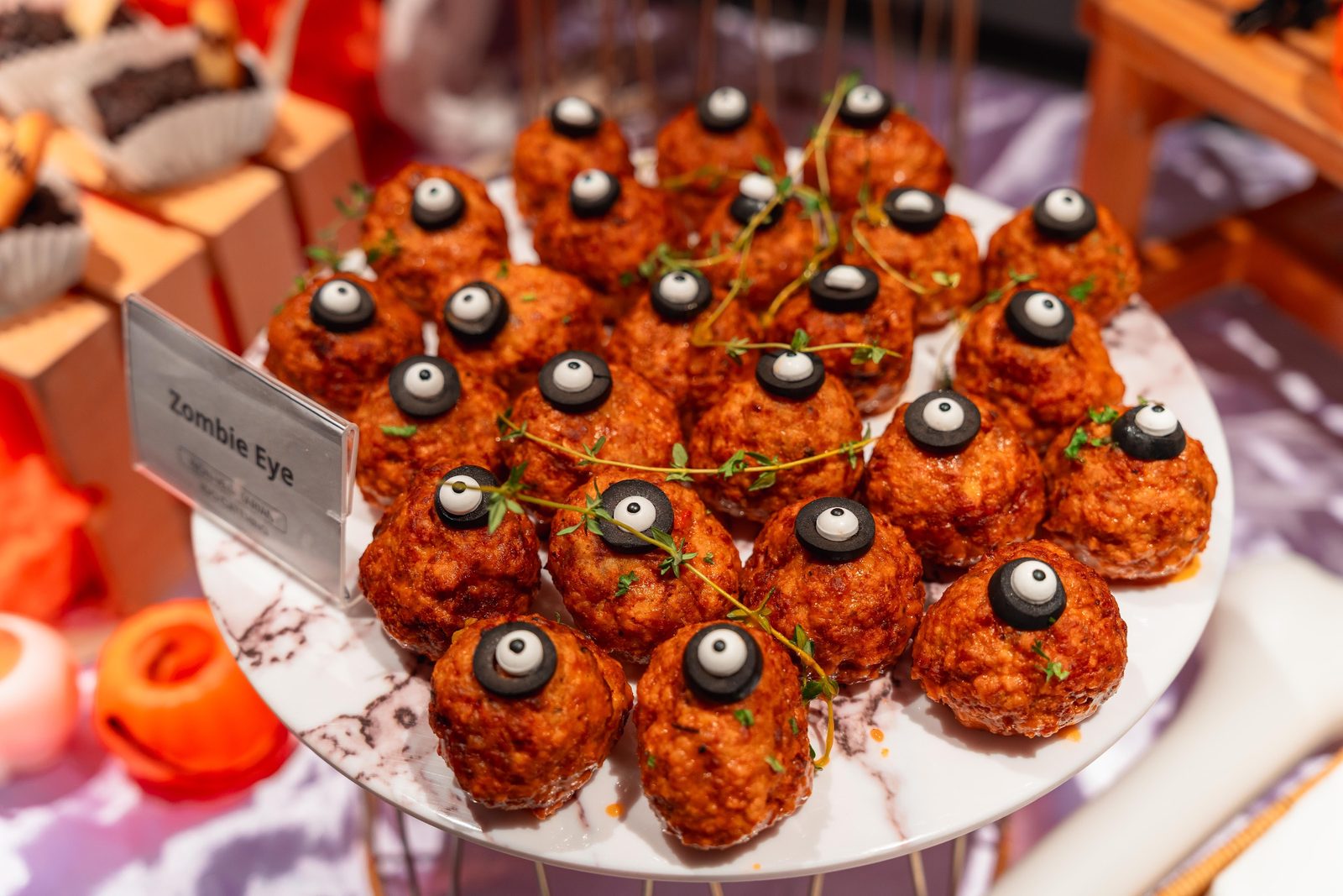 Zombie Eye chicken meatballs topped with olive eyeballs on a marble stand at an iDoCatering Halloween party