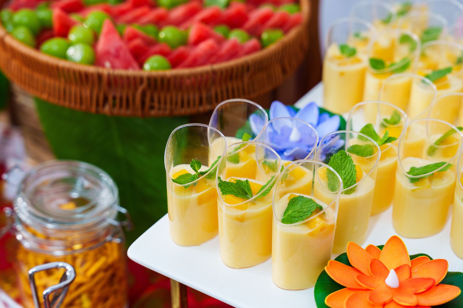 Mango pudding cups topped with mint beside a watermelon and grape platter at an iDoCatering Deepavali buffet