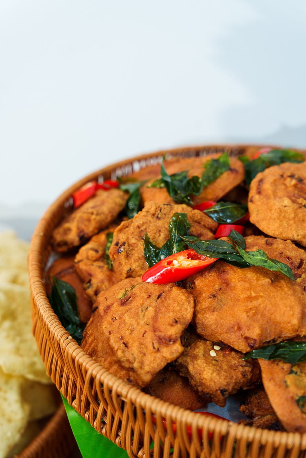 Crisp vadai topped with fried curry leaves and red chilli in a rattan basket at an iDoCatering Deepavali buffet
