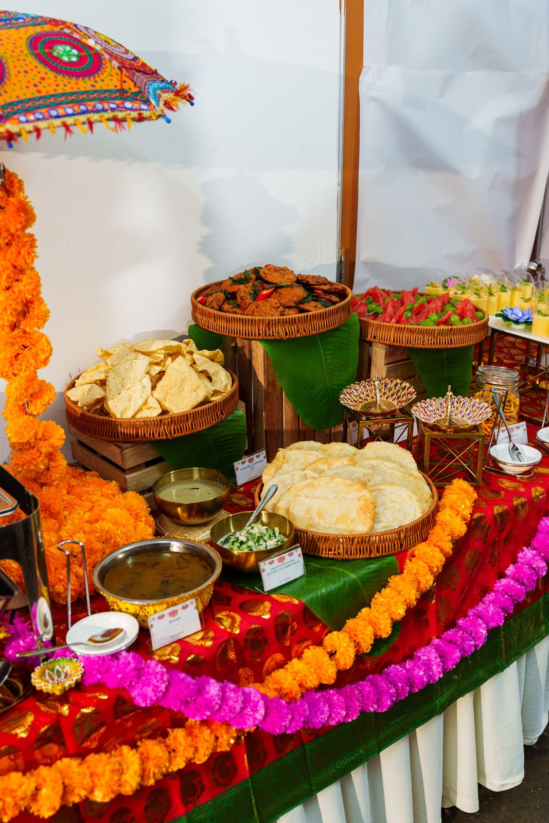 Rattan baskets of papadom, vadai and paratha on banana leaves with marigold garlands at a Deepavali buffet