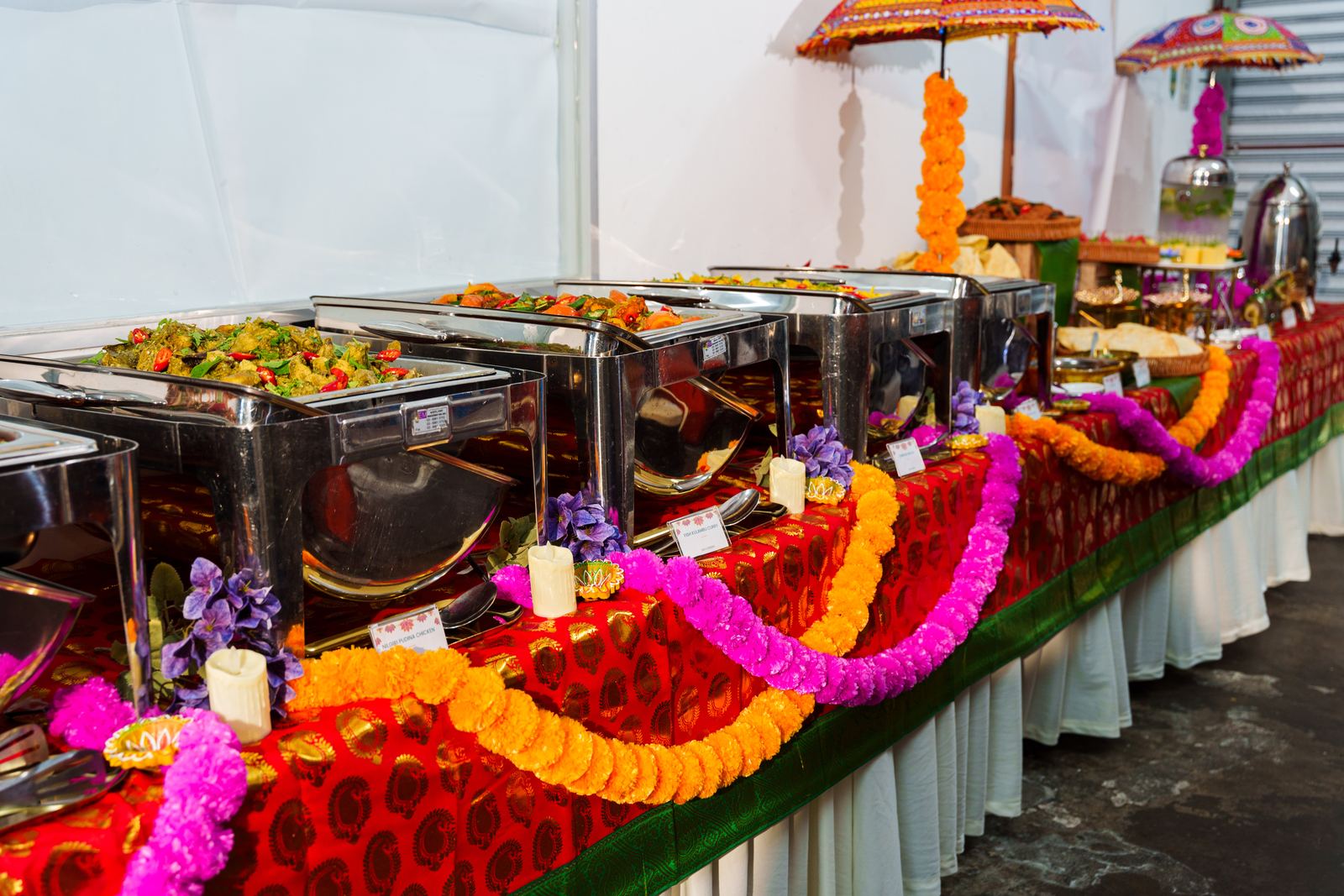 Deepavali buffet line of chafing dishes dressed with marigold garlands and embroidered umbrellas by iDoCatering
